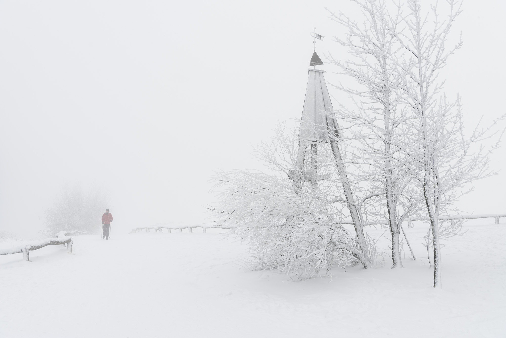 Kaum sichtbarer Mann im Schneetreiben auf dem Grosser Feldberg im Taunus.