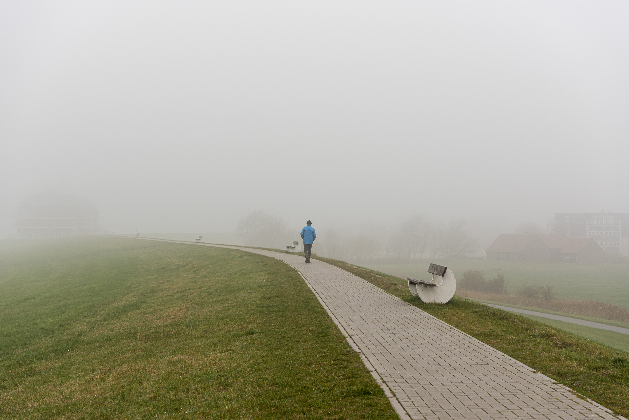 Mann auf einen Fussweg im Nebel auf Deich.