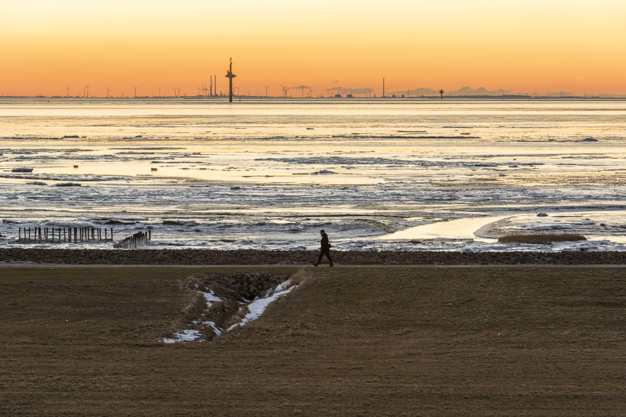 Mann vor Sonnenuntergangkulisse an der Nordsee.